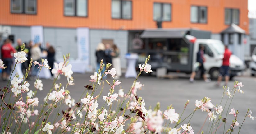 Invigningsfest på Röntgenvägen 5 i Flemingsberg, blommor i förgrunden framför mingel vid pizzatruck.