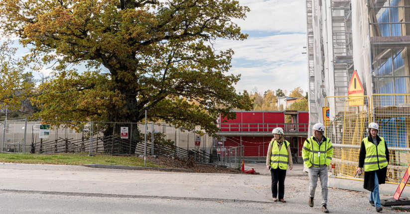 Tre personer går vid ett nybyggt hus